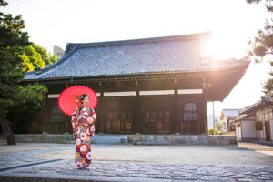 a woman in a traditional japanese dress holding a red umbrella
